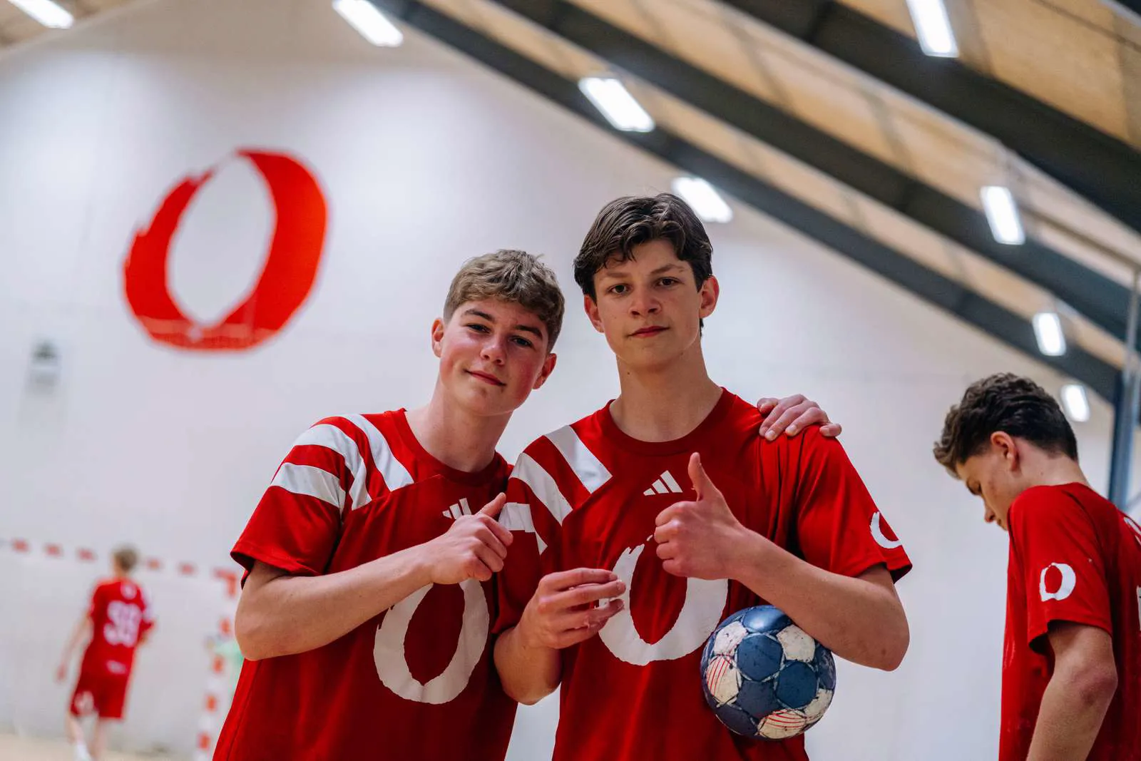 To håndbolddrenge smiler til kameraet i hallen