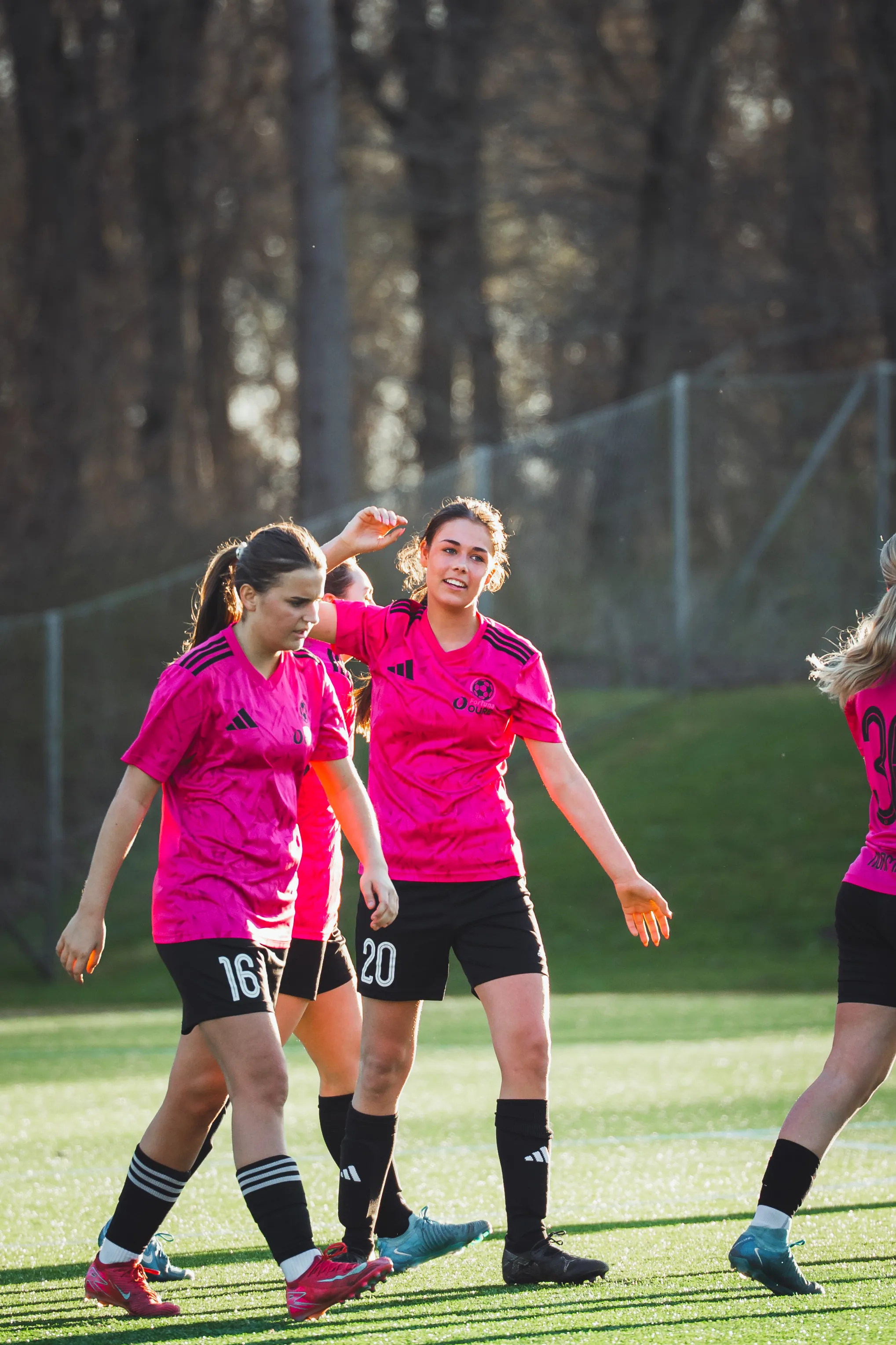 To piger i pink fodboldtøj, der spiller fodbold