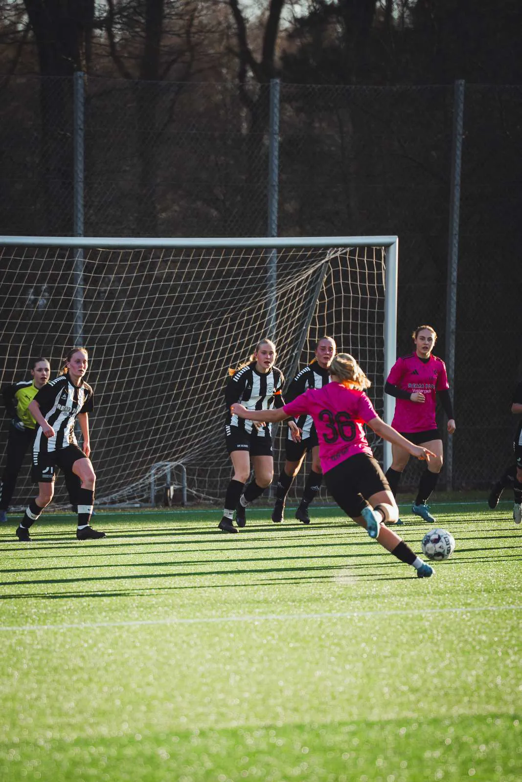 Fodboldkamp hvor en pige skyder på mål