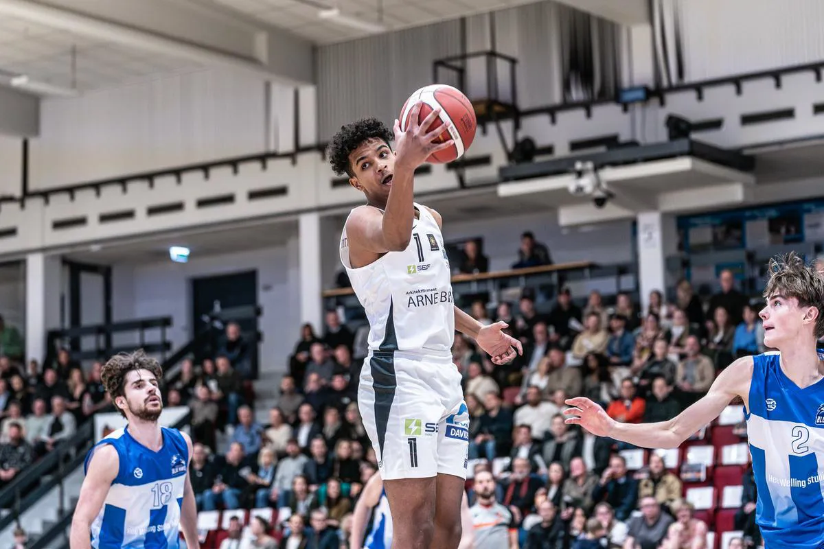 Basketspiller i kamp med bolden i hånden