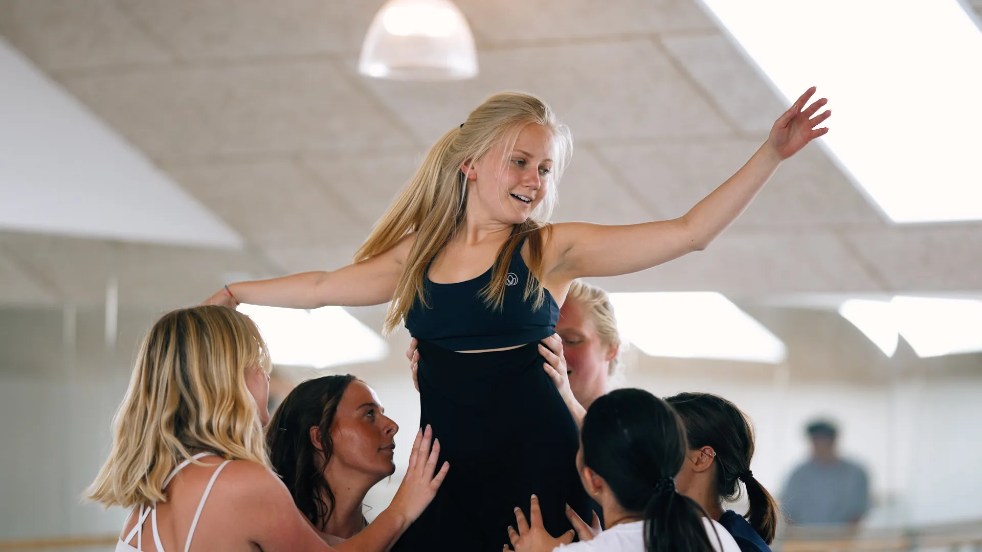 Gymnasieelver, der danser i en flok og holder en af pigerne oppe i midten