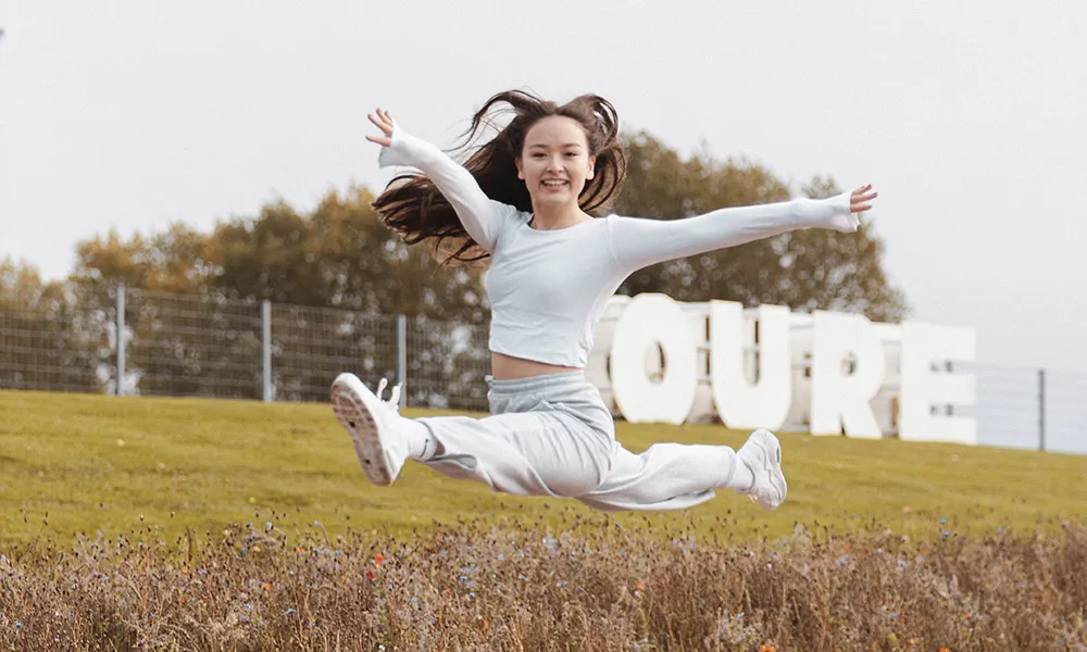 Danseelev laver et hop foran Oure-skilt
