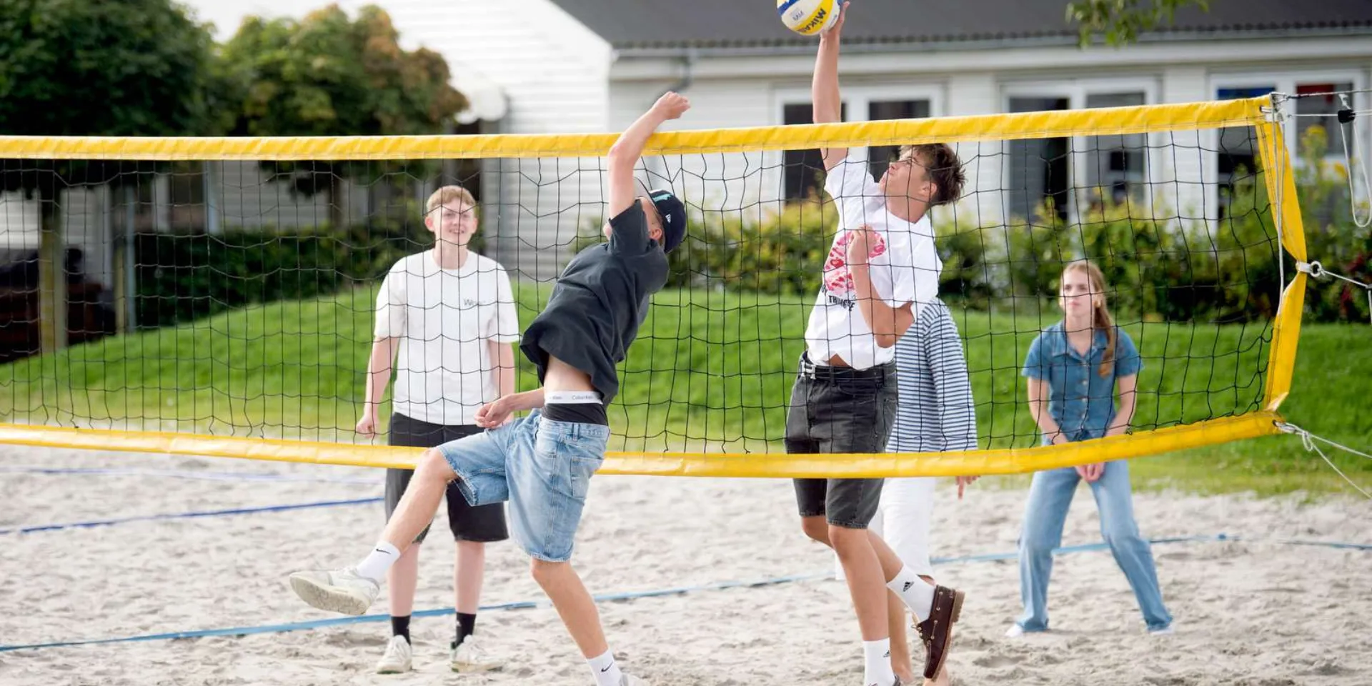 Unge gymnasieelever, der spiller beachvolley