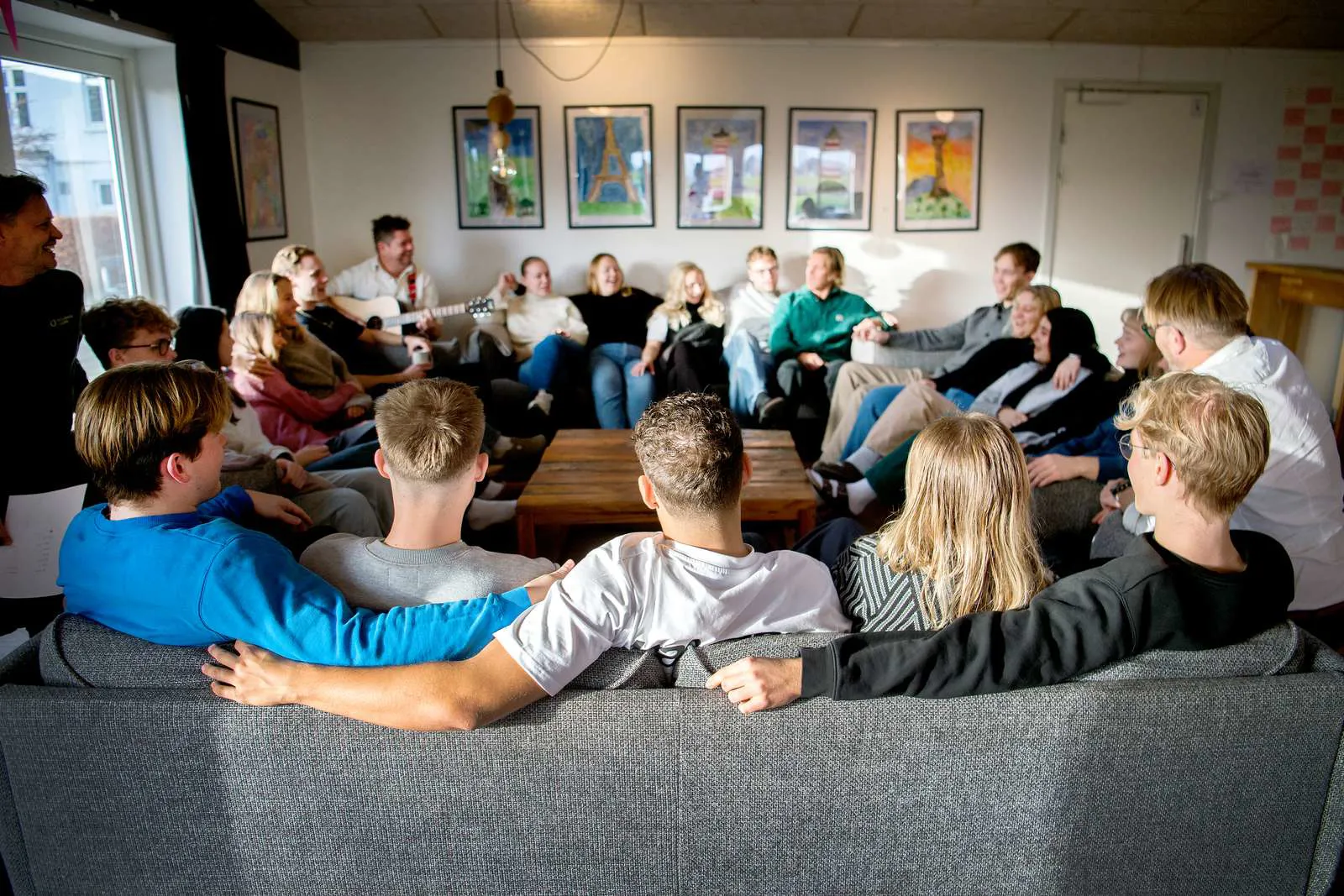Højskoleelever der sidder i sofa og synger fællessang