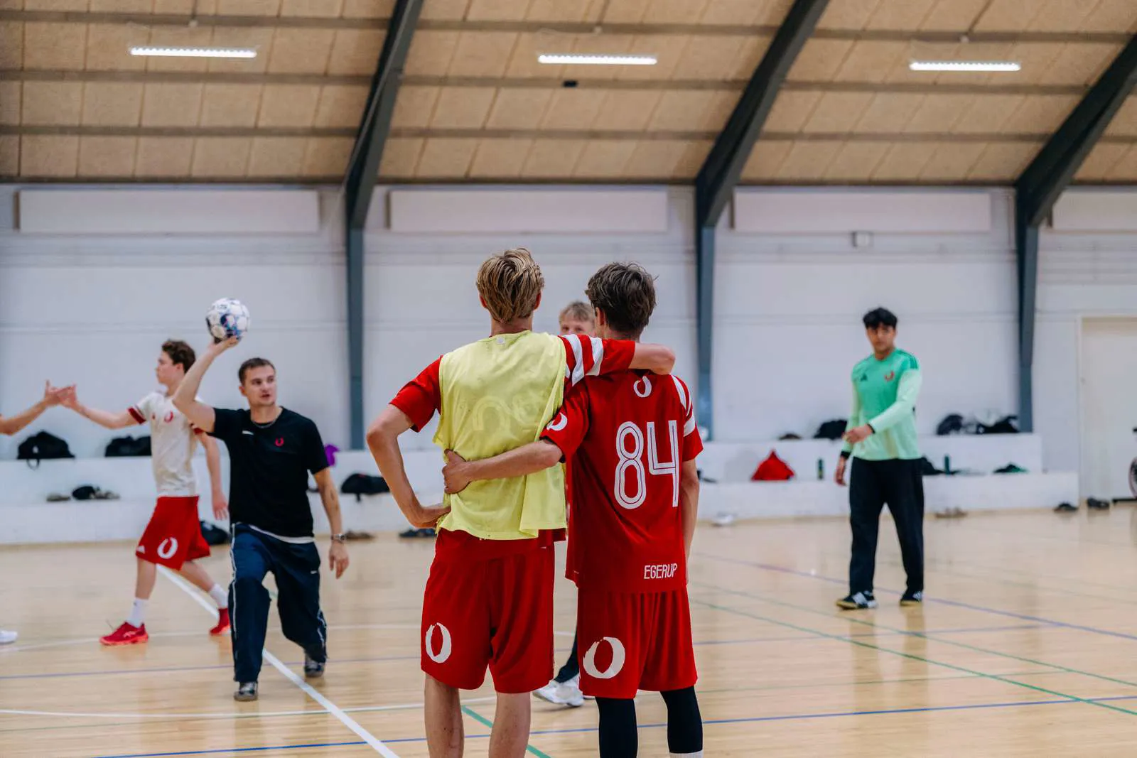 To håndbolddrengespillere holder rundt om hinanden i hallen
