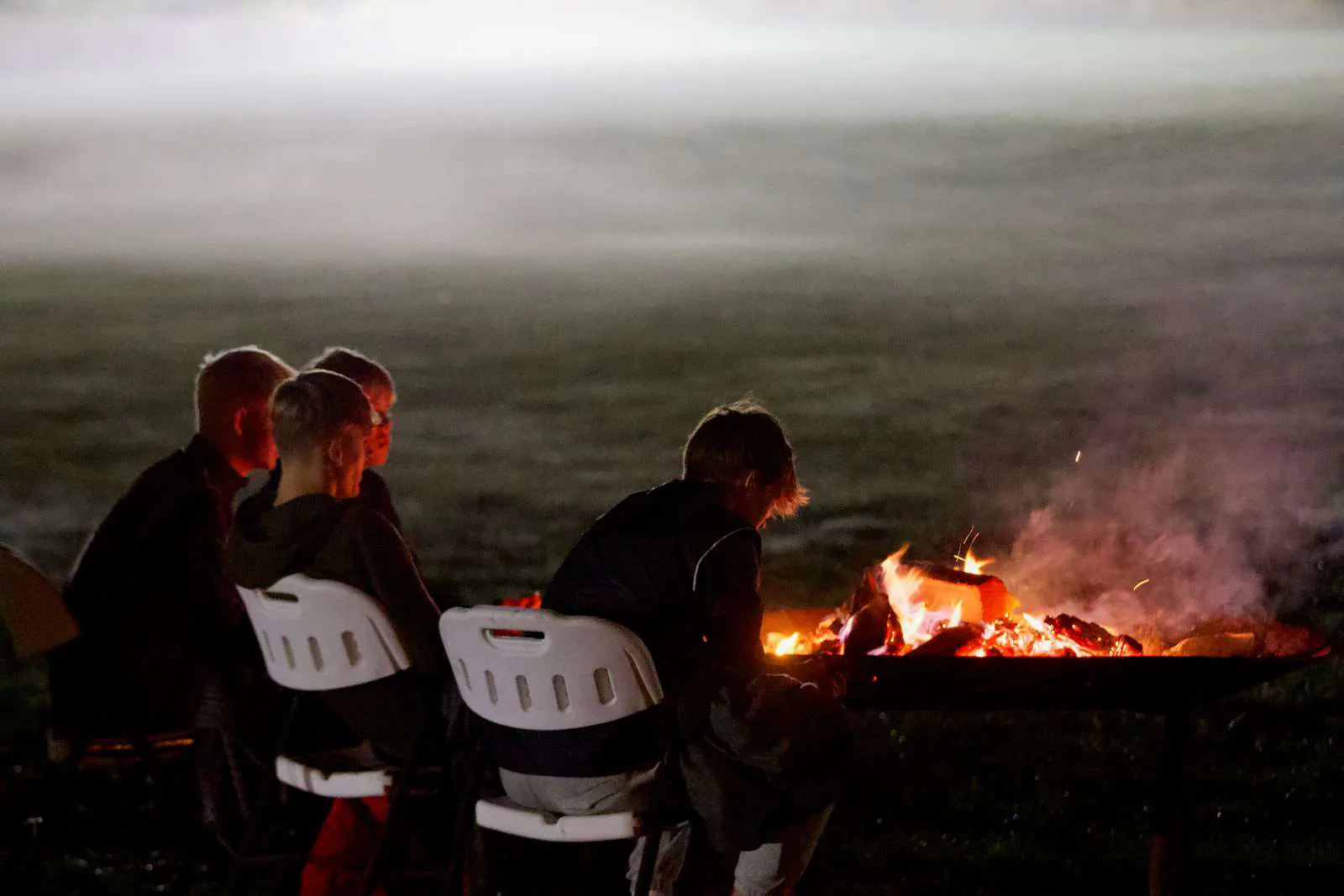 Fodbolddrenge, der sidder ved bålet